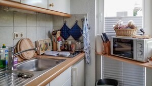 A kitchen with a stainless steel sink, wooden countertop, and a microwave. There are various kitchen utensils and a basket of bread on the counter. - 1 bedroom awesome apartment in Sassnitz (Sassnitz)