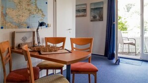 A dining area with a wooden table, four chairs, a map on the wall, and a balcony with a chair. - 1 bedroom awesome apartment in Sassnitz (Sassnitz)