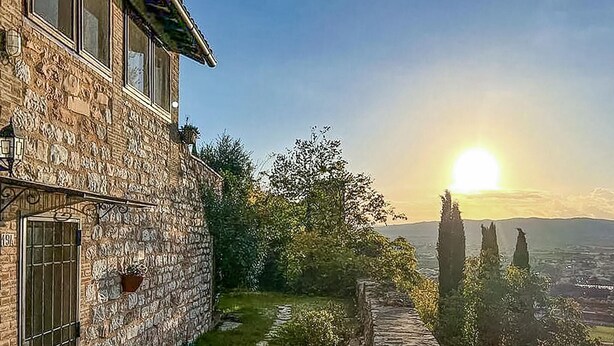 A stone building with a window, a door, and a small garden area with a pathway. - Casa Porta Fontevecchia (Spello)