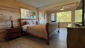 Ein Schlafzimmer mit Holzwandverkleidung, einem Bett, Nachttischen und einer Kommode.