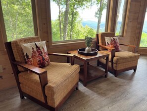 Una stanza accogliente con mobili in legno, ampie finestre e vista sugli alberi.