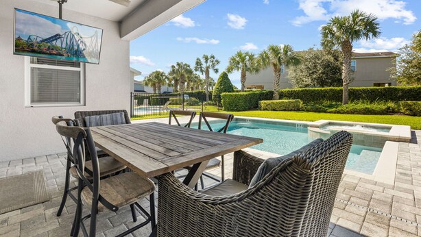 Patio esterno con piscina, mobili in vimini e una ventola a soffitto.