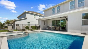 Una casa moderna a due piani con piscina, area salotto esterna e giardino recintato.