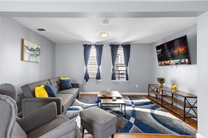 A modern living room with a grey sofa, a coffee table, and a TV on the wall.