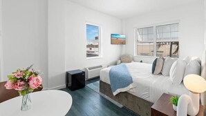 Une chambre moderne avec un lit, une table de chevet, une lampe et une fenêtre avec des stores.