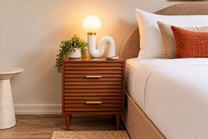 Een nachtkastje van hout met lades, een lamp en een kleine plant.