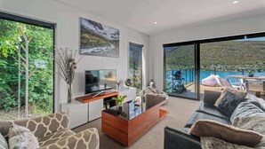 Ein modernes Wohnzimmer mit Sofa, Couchtisch, Fernseher und Seeblick.