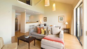 A spacious living room with a sofa, a coffee table, and a dining area in the background.