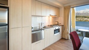 A modern kitchen with stainless steel appliances, a window with a mountain view, and a dining area with a red chair.