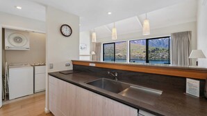 Una cocina moderna con un amplio ventanal, armarios de madera y un lavamanos empotrado.