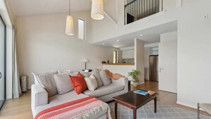 Una sala de estar moderna con un sofá gris, una mesa de centro de madera y una manta roja.
