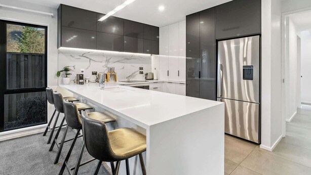 A modern kitchen with a central island, bar stools, a stainless steel refrigerator, and a large window. - Gallerie Coronet Summ (Queenstown)