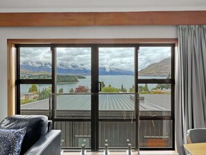 Una habitación con un amplio ventanal que ofrece vistas a un lago, montañas y una isla distante.