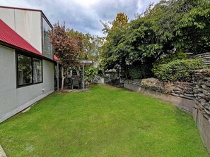 A well-maintained backyard with a patio, a stone wall, and a grassy lawn.