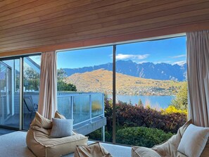 A modern room with a large window overlooking a mountainous landscape and a lake.