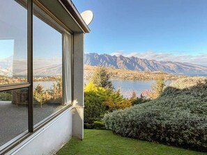 A modern building with large windows overlooking a lake and mountains.