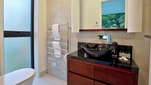 Une salle de bain moderne avec une grande fenêtre, un lavabo noir en forme de vasque, un porte-serviettes et un miroir orné d’une peinture représentant un arbre.