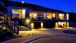 Une maison moderne à deux étages, dotée d’un balcon spacieux, de grandes fenêtres et d’une entrée bien éclairée.