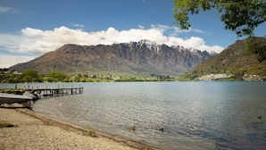 Ein See mit Bergen im Hintergrund, eine Anlegestelle und ein kleines Dorf.