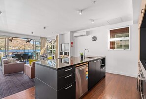 A modern kitchen with a dishwasher, a sink, and a window with blinds.