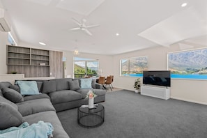 A modern living room with a sectional sofa, a flat-screen TV, and a view of a lake.