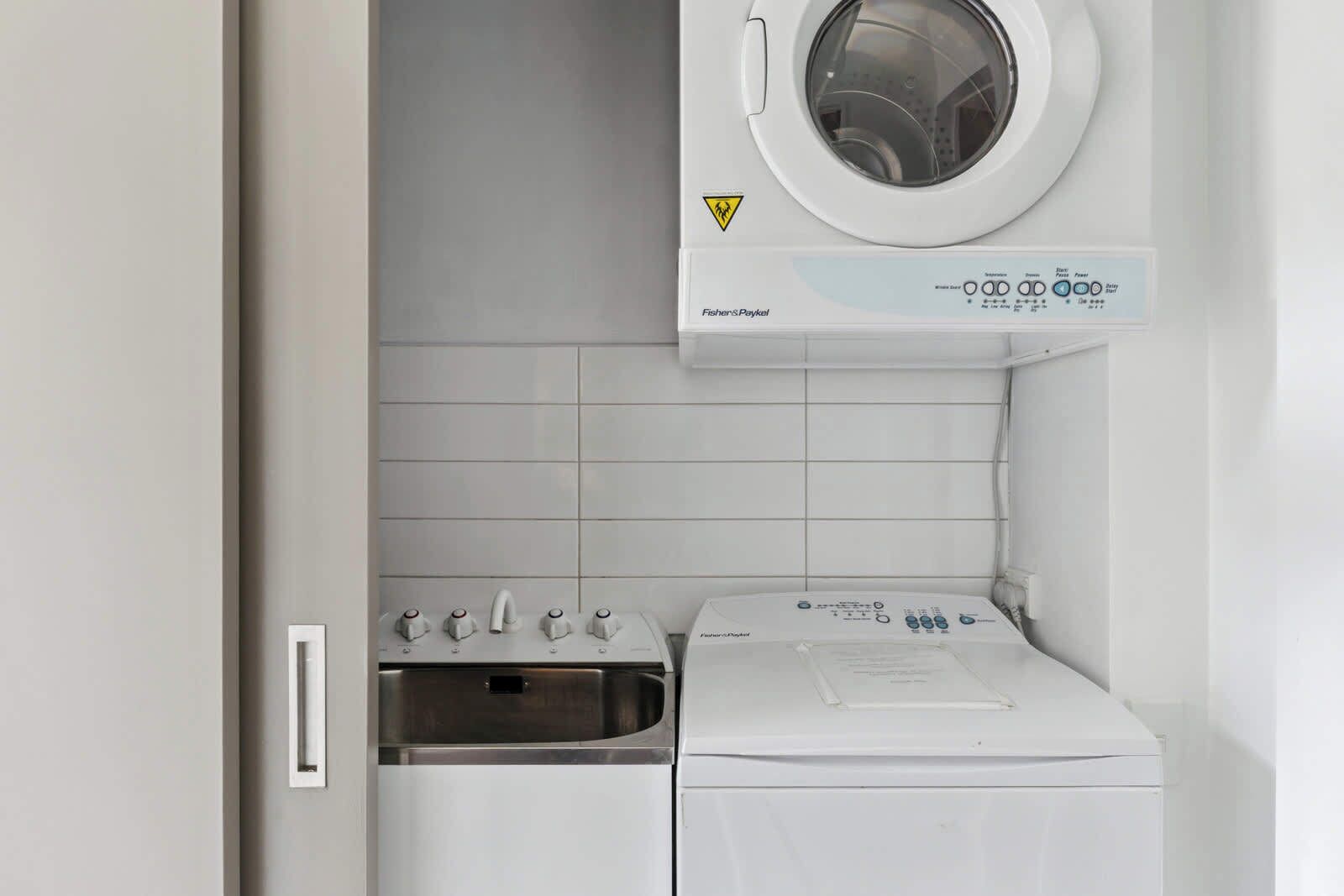 Een kleine wasruimte met een voorlader wasmachine en een droger met bovenlader.