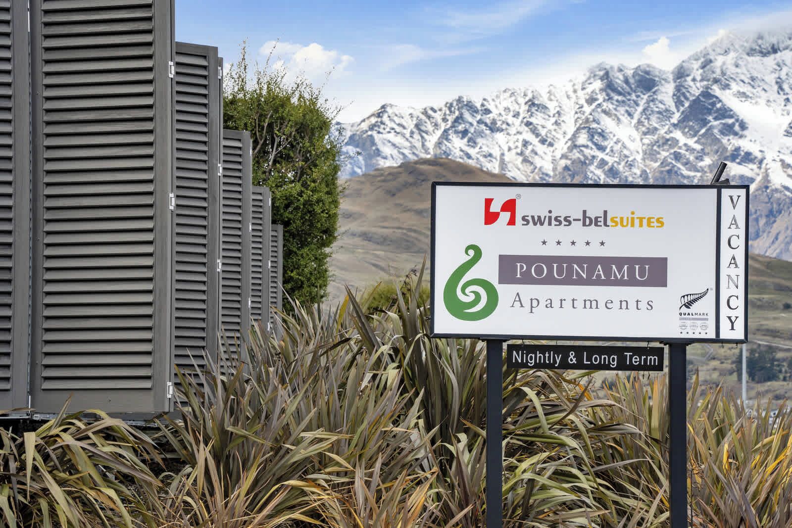 Une enseigne pour les appartements Pounamu, avec une chaîne de montagnes en arrière-plan.
