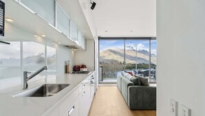 A modern kitchen with a large window, a built-in stove, and a sink. - Lakeview Premium 2 Bed Apartment Pounamu 203 (Queenstown)