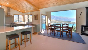 A modern kitchen with a large island, bar stools, and a dining area with a view of mountains.