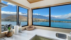 A kitchen with large windows, a view of mountains, and a lake.