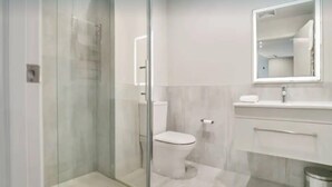 A modern bathroom with a glass-enclosed shower, a toilet, and a vanity with a mirror. - Studio Getaway, Remarkables Views, Frankton (Queenstown)