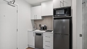 A modern kitchen with white cabinets, a stainless steel refrigerator, a microwave, and a dishwasher. - Studio Getaway, Remarkables Views, Frankton (Queenstown)