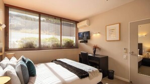 Un dormitorio moderno con una cama grande, un escritorio y un televisor.