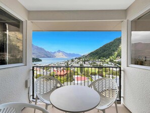 Un balcón con mesa y sillas, con vistas a un pueblo y montañas.