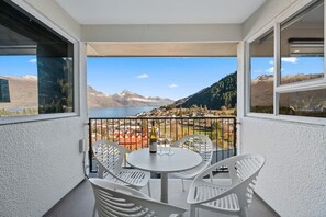 Un balcón con mesa y sillas, con vistas a un lago y montañas.