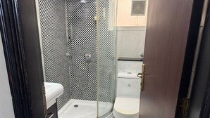 A small bathroom with a toilet, a shower, and a sink.