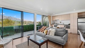 A modern living room with a grey sofa, a coffee table, and a view of mountains through large windows.