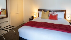 A hotel room with a bed, a nightstand, a bedside lamp, a chair, and a wardrobe.