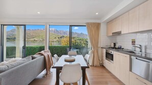 A modern kitchen with a dining area, large windows with a mountain view, and light-colored cabinetry.