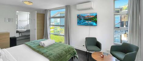 Una habitación de hotel con una cama, televisor, silla y una mesita.