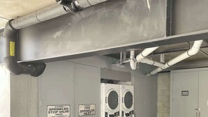 A parking garage with a fire sprinkler system, a washing machine, and a blue bag on the floor.