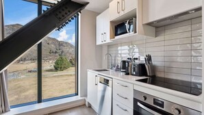A modern kitchen with white cabinetry, a built-in microwave, and a dishwasher. - Modern apartment with fantastic mountain views! (Queenstown)