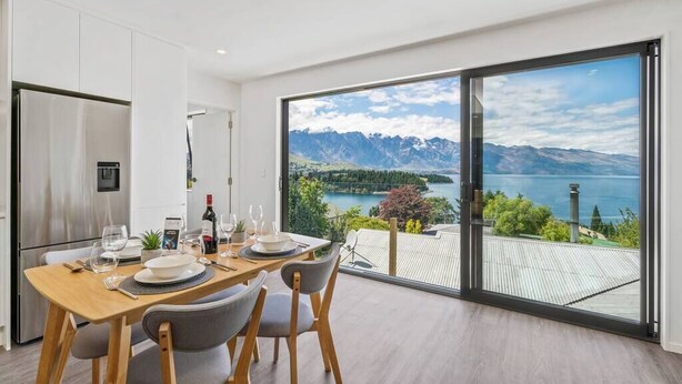 A modern dining area with a view of mountains and a lake.