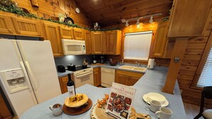 A kitchen with wooden cabinets, a refrigerator, a microwave, a stove, and a sink. There is a book titled "The Cajun & Creole Cookbook" on the counter.