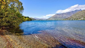 Un lago limpido con una riva rocciosa e una sponda alberata.