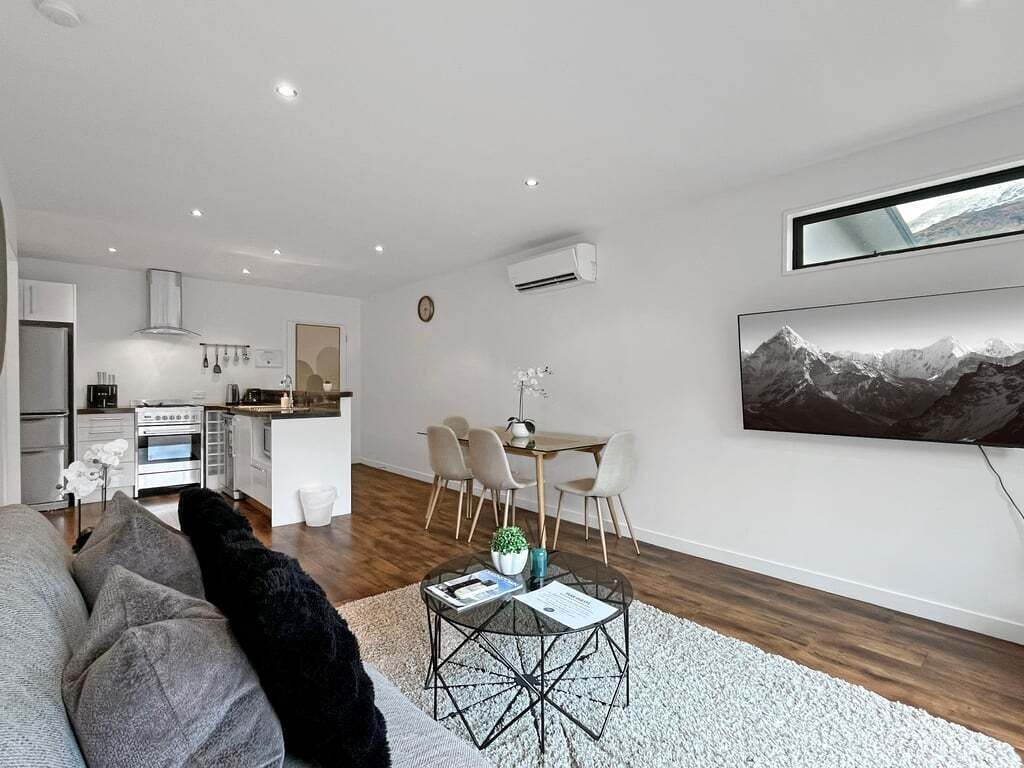 A modern living room with a sofa, a coffee table, and a dining area with chairs.