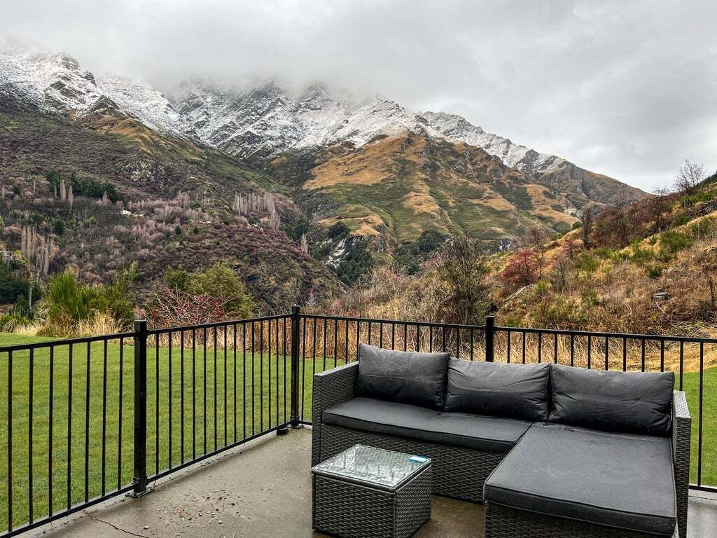 A balcony with a black metal railing, a black sofa, and a glass coffee table.
