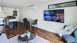 Ein moderner Wohnraum mit Essbereich, Küche und großem Wandfernseher.