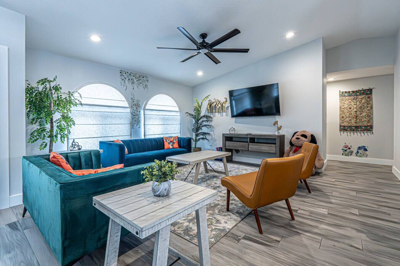 Un salon moderne avec un canapé de couleur turquoise, une table basse en bois et un ventilateur de plafond.