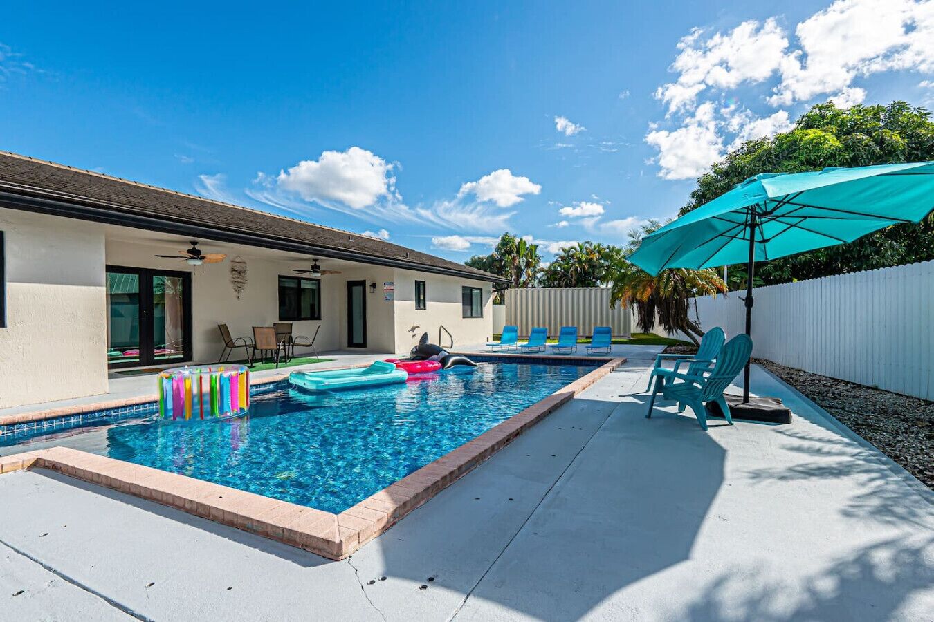 A swimming pool with lounge chairs and a ceiling fan.